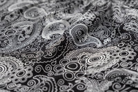 Black paisley rayon flow pants fabric close-up, swirling circular pattern